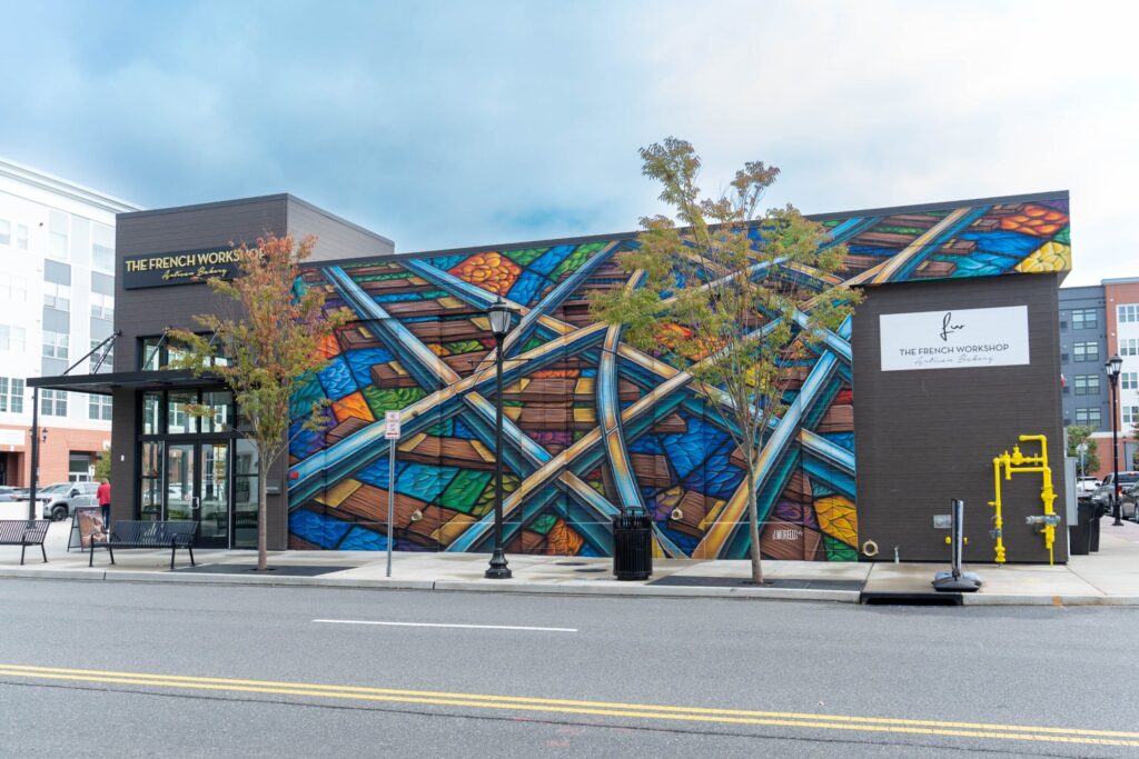 Jenna Morello's colorful Passing Through mural of crisscrossing train tracks on The French Workshop at Station Yards in Ronkonkoma